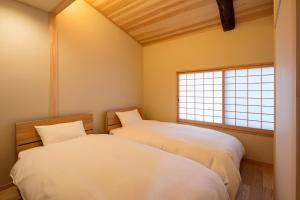 twee bedden in een kamer met twee ramen bij Shimabara Kaiden Machiya House in Kyoto