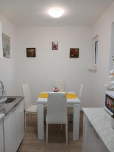 a white kitchen with a white table and white chairs at APARTMAN Verica 2025 in Vrdnik