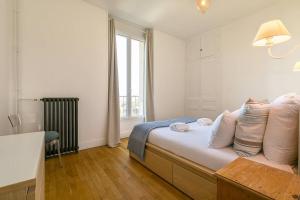a bedroom with a bed with pillows and a window at Le Victor Hugo in Dijon +5 photos