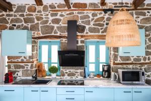 a kitchen with blue cabinets and a stone wall at House Marika - between Sea & mountains in Sykia Chalkidikis +25 photos