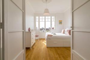 a white bedroom with a bed and a window at Le Victor Hugo in Dijon