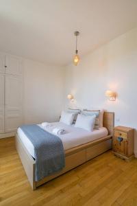 a bedroom with a large bed with white walls at Le Victor Hugo in Dijon