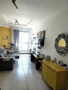 a living room with a couch and a mirror on the wall at Apartamento em Guarapari in Guarapari