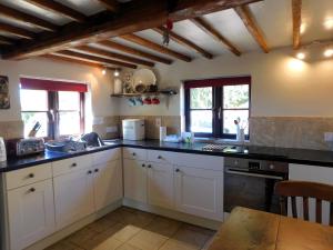 a kitchen with white cabinets and black counter tops at Beechwood Cottage in Filby +20 photos