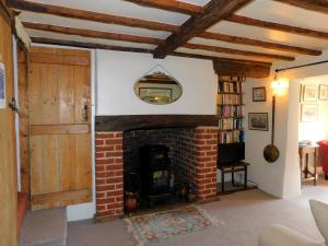 a living room with a brick fireplace and a door at Beechwood Cottage in Filby