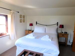 a bedroom with a large white bed with towels on it at Beechwood Cottage in Filby