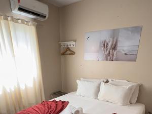 a bedroom with a bed with white pillows and a window at Casa do Anjo in Fernando de Noronha