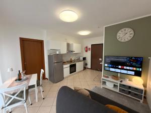 a living room with a couch and a kitchen with a clock at Malpensa Stay Express Self check-in in Gallarate