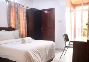 a bedroom with a bed and a chair and a window at Aotel Hotel Lagos Owodunni in Ikeja