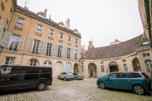 two cars parked in front of a large building at Le Cote D'Or in Dijon