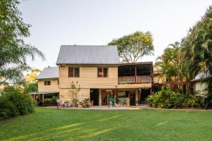 a wooden house with a porch and a yard at Glasshouse Mountains Ecolodge in Glass House Mountains