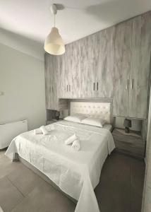 a bedroom with a large white bed with towels on it at Arientas Apartment in Ermoupoli