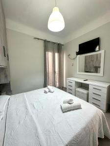 a bedroom with a white bed with two towels on it at Arientas Apartment in Ermoupoli