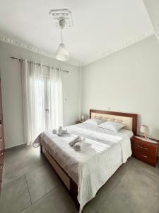 a white bedroom with a large bed and a window at Arientas Apartment in Ermoupoli