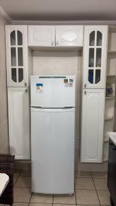 a white refrigerator in a kitchen with white cabinets at Ap Praia das Pitangueiras in Guarujá