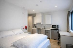 a bedroom with a bed and a kitchen with a microwave at Destiny - Burnet Point in Edinburgh