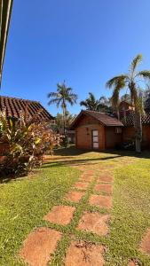 a yard with a house and palm trees andgrass at Hotel Cabañas Del Parque in Oberá