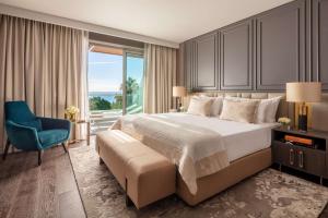 a bedroom with a large bed and a blue chair at Anantara Plaza Nice Hotel - A Leading Hotel of the World in Nice