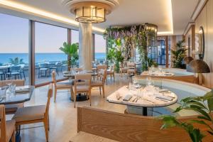 a restaurant with tables and chairs and a view of the ocean at Anantara Plaza Nice Hotel - A Leading Hotel of the World in Nice