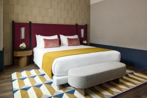 a bedroom with a large bed and a ottoman at Tivoli President Milano Hotel in Milan +60 photos