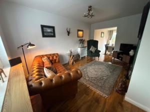 a living room with a brown leather couch at Holly Berry Cottage in Holme next the Sea