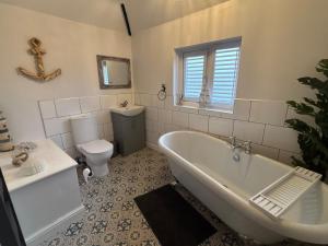 a bathroom with a tub and a toilet and a sink at Holly Berry Cottage in Holme next the Sea +15 photos
