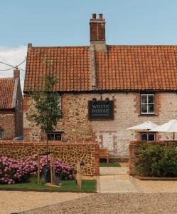 a brick building with a sign for a white house at Holly Berry Cottage in Holme next the Sea