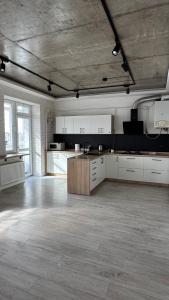 a large room with a kitchen with white cabinets at Spacious modern loft on Perfetskogo in Lviv