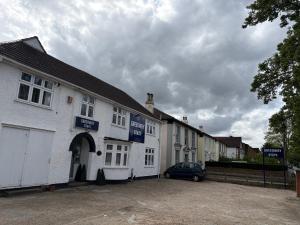 a white building with a car parked in front of it at OYO Greenway Stays in Uxbridge