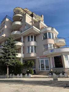 a large white building with a tree in front of it at Hotel Andre in Burgas