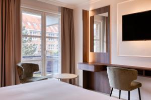 a hotel room with a bed and two chairs and a window at Golden Tulip Hotel de’ Medici in Bruges