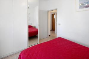 a bedroom with a red bed and a mirror at Erikbeach Bilo in Bibione