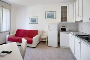 a kitchen with a red chair and a couch at Erikbeach Bilo in Bibione