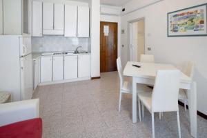 a kitchen with white cabinets and a white table and chairs at Erikbeach Bilo in Bibione +7 photos