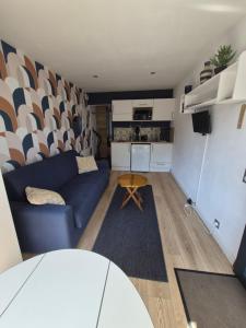 a living room with a blue couch and a kitchen at Guest House in Gévezé