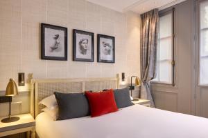 a bedroom with a white bed with four pictures on the wall at Charles V in Paris