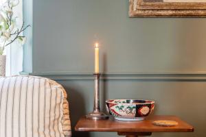 a candle on a table next to a chair with a bowl at Grand Georgian Residence in Bath