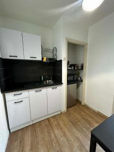 a kitchen with white cabinets and a wooden floor at Appartement carmes in Aurillac
