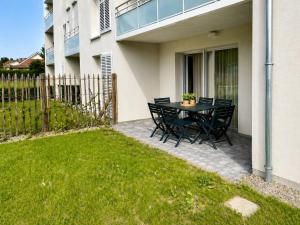 a patio with a table and chairs in a yard at L'Orée des Pins - Suite parentale - Merlimont in Merlimont