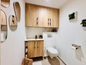 a bathroom with a toilet and wooden cabinets at L'Orée des Pins - Suite parentale - Merlimont in Merlimont +36 photos