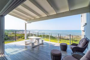 a patio with a table and chairs and the ocean at Klipfontein House in Kleinbaai