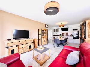 a living room with a red couch and a flat screen tv at L'Orée des Pins - Suite parentale - Merlimont in Merlimont