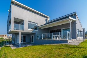 a house with a large balcony with a lawn at Klipfontein House in Kleinbaai