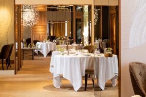 a restaurant with white tables and chairs and a mirror at Hôtel Lion d'Or 1774 - Châteaux de la Loire in Romorantin