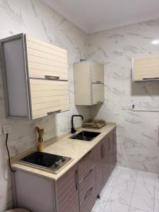 a kitchen with a sink and white marble walls at منازل الجود , أبحر - Manazil Al Joud , Obhour in Jeddah