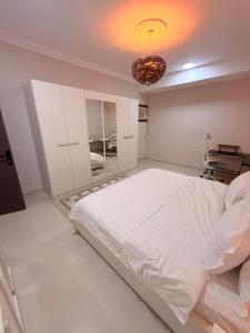 a bedroom with a large white bed and a chandelier at منازل الجود , أبحر - Manazil Al Joud , Obhour in Jeddah