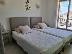 two beds in a room with a window at Le Cabanon de Laura in L'Isle-sur-la-Sorgue