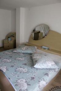a bedroom with a bed with a floral bedspread and a mirror at Vikendica Drinska Flora, Loznica - Lipnički Šor in Lipnički Šor