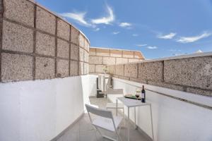 a balcony with a table and chairs on a brick wall at Olivia’s Beach in Candelaria