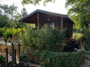 a small wooden building in a garden with a fence at L'arbousier in Clermont-lʼHérault